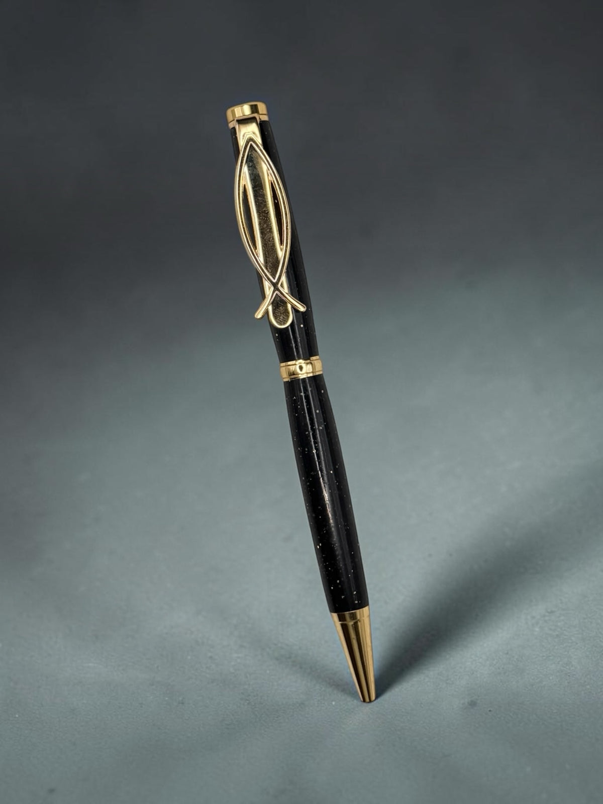 Anderson Woodworks handcrafted black ballpoint pen with shimmering flecks and a unique gold-tone fish-shaped clip.