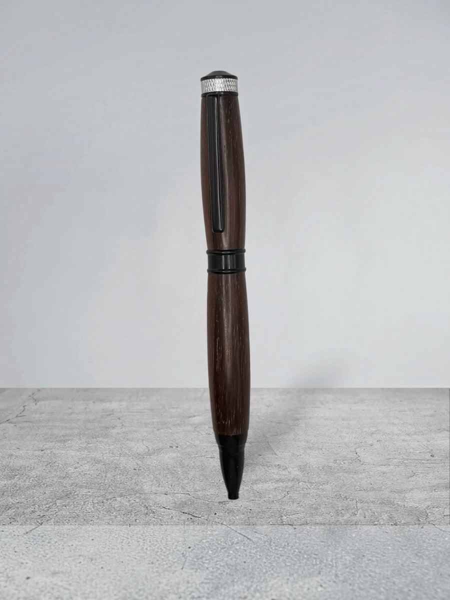 Anderson Woodworks handcrafted dark wood ballpoint pen with matte black hardware and silver knurled cap detail.