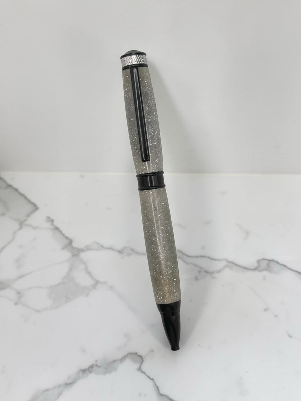 Anderson Woodworks handcrafted writing pen with a translucent grey glitter barrel and sleek dark hardware accents.
