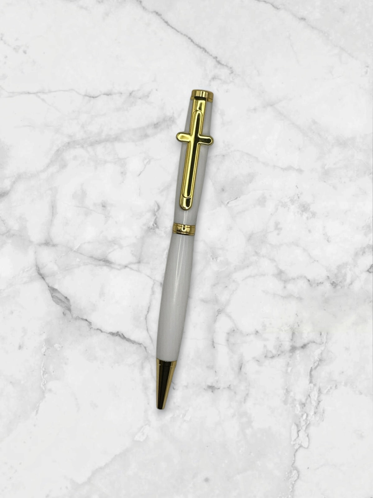 Anderson Woodworks white ballpoint pen with gold-tone cross clip and accents on a textured white background.
